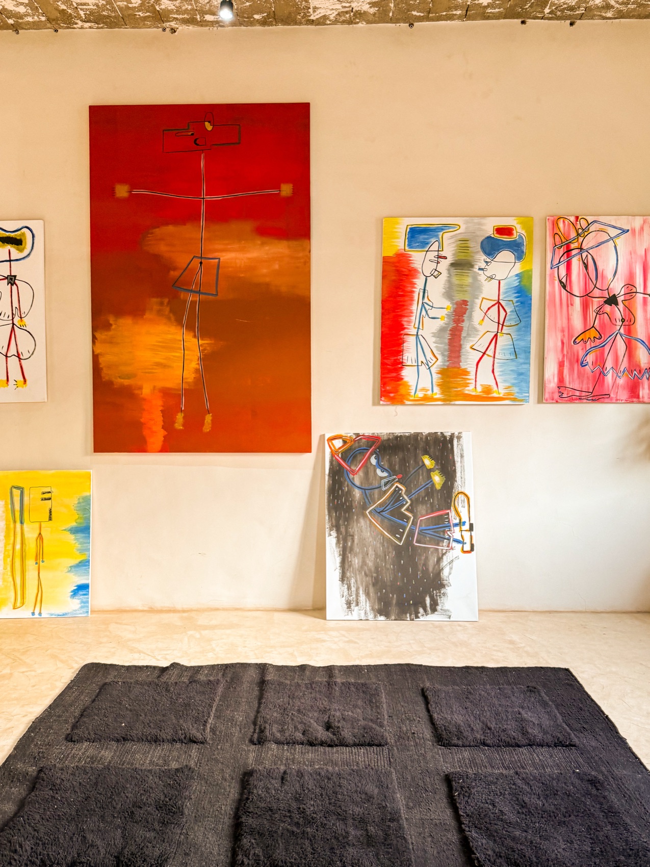 Wall of paintings and a dark tufted rug